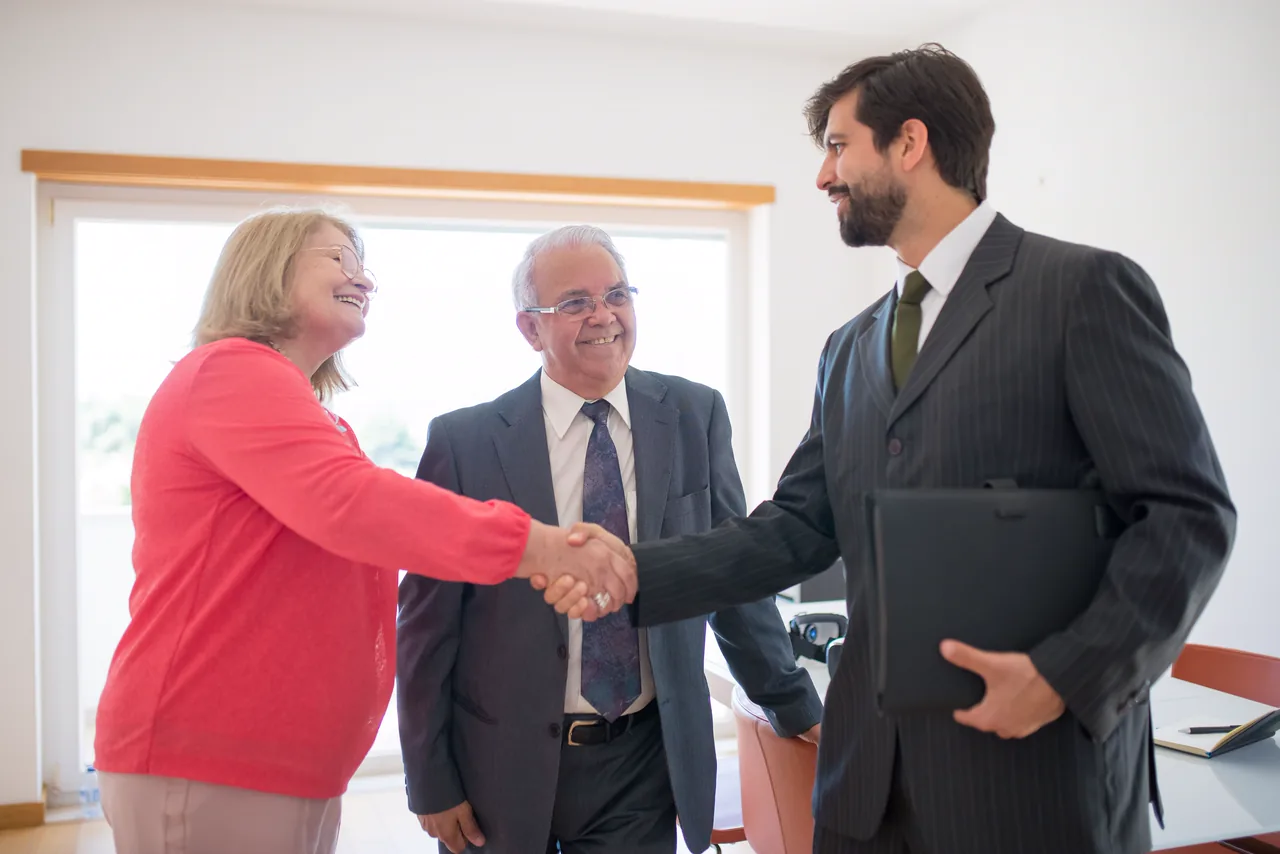 An attorney shaking hands with a smiling couple